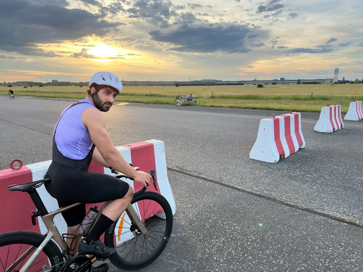 Riding a road bike on the open tarmac of Tempelhofer Feld at sunset.